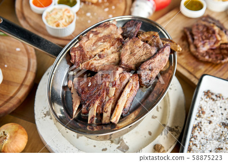 Various grilled meat set heated on coals. Barbecue restaurant menu. Many different food on the table Various grilled meat set heated on coals. Barbecue restaurant menu. Many different food on the table 58875223