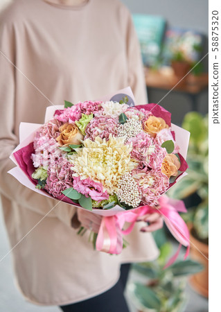 Beautiful bouquet of mixed flowers in womans hands. the work of the florist at a flower shop Beautiful bouquet of mixed flowers in womans hands. the work of the florist at a flower shop 58875320