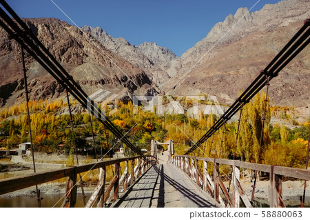 Wooden suspension bridge leads to Khalti village in autumn season against Hindu Kush mountain range Wooden suspension bridge leads to Khalti village in autumn season against Hindu Kush mountain range 58880063