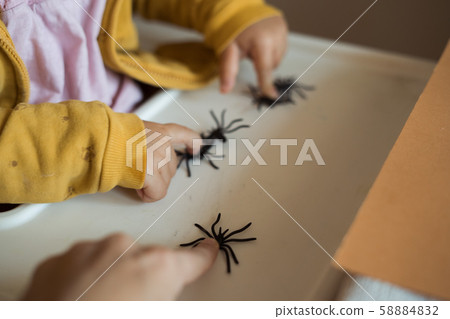 Hands of a child playing with black rubber spiders toys. Halloween october concept. Hands of a child playing with black rubber spiders toys. Halloween october concept. 58884832
