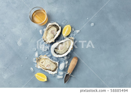 Fresh raw oysters, overhead shot on ice with a glass of white wine, lemon slices, shucking knife and Fresh raw oysters, overhead shot on ice with a glass of white wine, lemon slices, shucking knife and 58885494