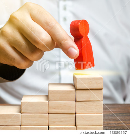 A man puts a red human figure on top of the stairs. Career growth, improvement of skills. Promotion at work of employees to leading post. The concept of success. Training. Education, business A man puts a red human figure on top of the stairs. Career growth, improvement of skills. Promotion at work of employees to leading post. The concept of success. Training. Education, business 58889367