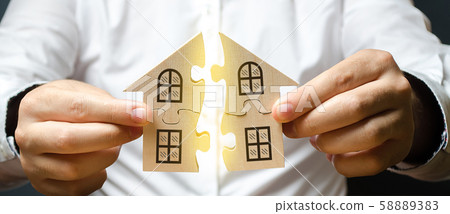 A man connects two puzzles into a whole house above the inscription Mortgage. Construction of your own residential building. Buying a home on credit loan, improvement of living conditions A man connects two puzzles into a whole house above the inscription Mortgage. Construction of your own residential building. Buying a home on credit loan, improvement of living conditions 58889383
