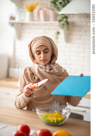 Pretty woman using bright kitchen tools while cooking 58891080