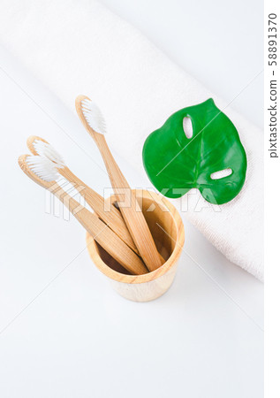 Bamboo toothbrushes in wooden glass with towel. Bamboo toothbrushes in wooden glass with towel. 58891370