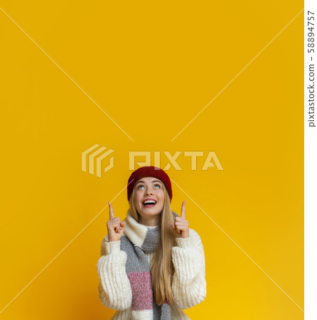 Amazed girl in red hat pointing up at copy space 58894757
