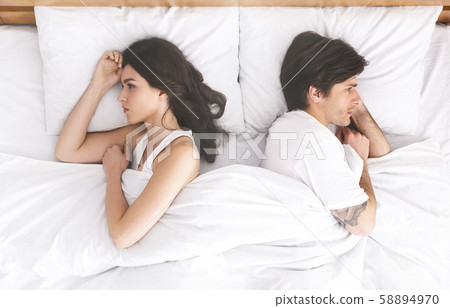 Upset couple ignoring each other, lying back to back in bed 58894970