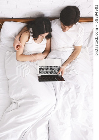 Young spouses watching movie together on laptop before sleeping 58894983