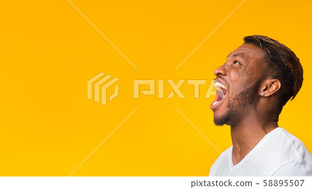 Black Guy Screaming Loudly Standing In Studio, Panorama, Side View Black Guy Screaming Loudly Standing In Studio, Panorama, Side View 58895507