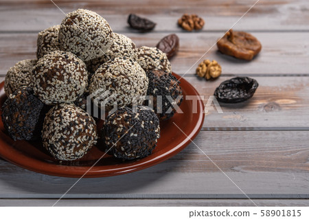 Homemade energy balls on a brown plate on a wooden background. Near the dried fruit 58901815