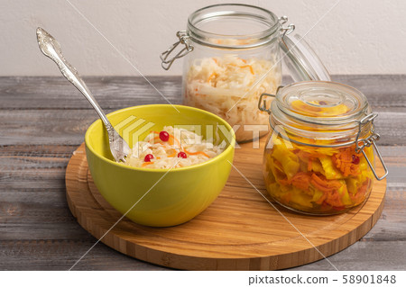 Homemade sauerkraut in two jars with a salad bowl and a fork on a wooden board. Rustic style Homemade sauerkraut in two jars with a salad bowl and a fork on a wooden board. Rustic style 58901848