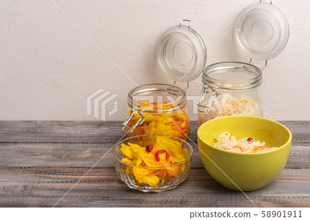 Homemade sauerkraut in glass jars with open lids and salad bowls on a wooden background. Rustic Homemade sauerkraut in glass jars with open lids and salad bowls on a wooden background. Rustic 58901911