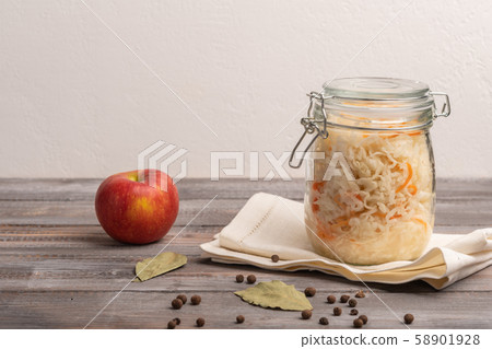 Homemade canned cabbage in jar on napkin with apple on a wooden table. Rustic style 58901928