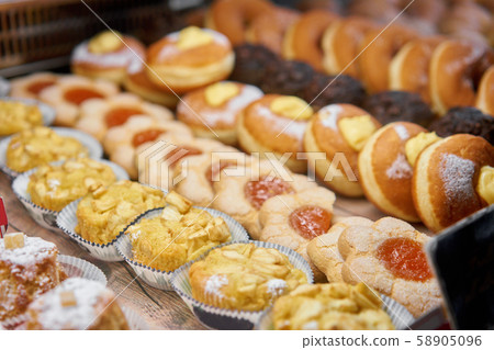 Donuts and rings. Hot pastries lie on the shelf in the cafe. Buns and chocolate muffins in the store 58905096