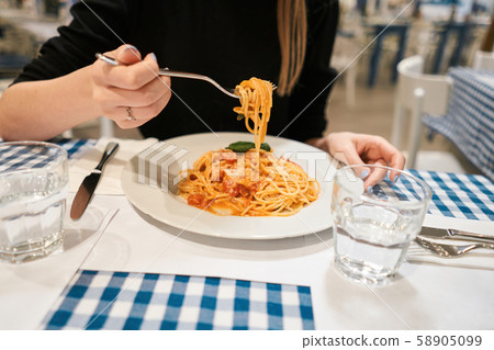 Close-up spaghetti Bolognese wind it around a fork. Parmesan cheese. Young woman eats Italian pasta 58905099