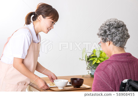 與老年婦女一起吃飯的照顧者和助手 與老年婦女一起吃飯的照顧者和助手 58908455