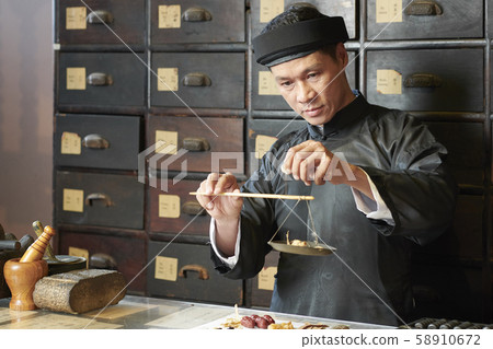 Medicine practitioner weighting herbs and roots 58910672