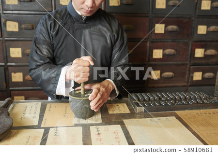 Drugstore worker grinding up ingredients in mortar 58910681