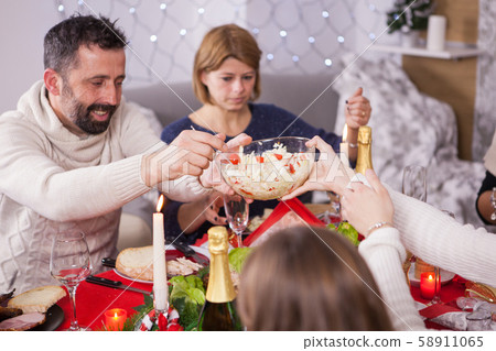 Adult man passing the salad over the table at family christmas feast Adult man passing the salad over the table at family christmas feast 58911065