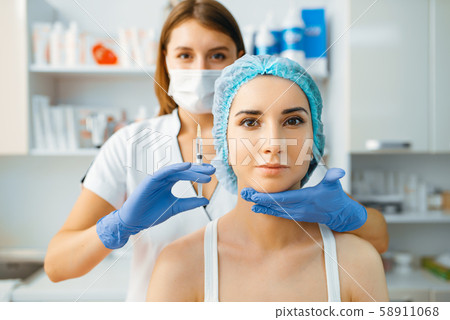 Cosmetician holds syringe with injection of botox Cosmetician holds syringe with injection of botox 58911068