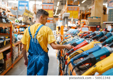 Builder choosing angle grinder in hardware store Builder choosing angle grinder in hardware store 58911348
