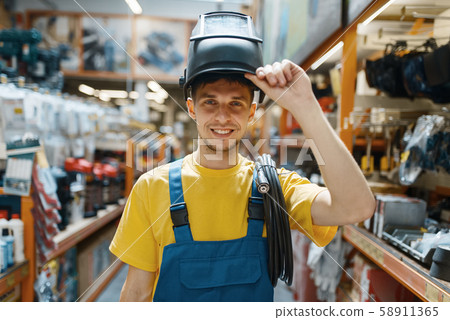 Builder choosing welding helmet in hardware store Builder choosing welding helmet in hardware store 58911365