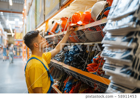 Male builder choosing helmet in hardware store 58911453