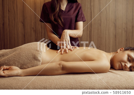 Female masseur pampering back to woman, massage Female masseur pampering back to woman, massage 58911650