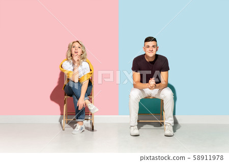Young emotional man and woman on pink and blue background 58911978
