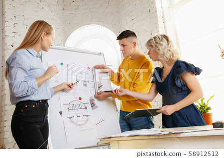 Interior designer working with young couple. Lovely family and professional designer or architector. Interior designer working with young couple. Lovely family and professional designer or architector. 58912512