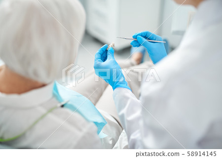Dental surgeon showing dental dentures to the patient 58914145