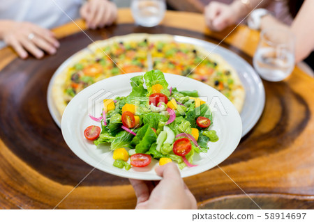 Waiter serving fresh vegetable salad in restaurant. 58914697