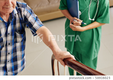 Nurse controlling walking senior patient 58916023