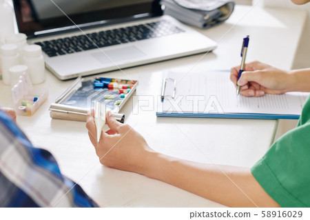 Nurse filling medical card of senior patient 58916029