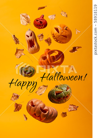 Several flying scary halloween pumpkins, dry leaves and inscription Happy Halloween Several flying scary halloween pumpkins, dry leaves and inscription Happy Halloween 58918119