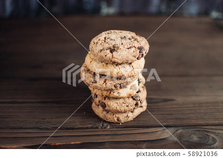 A stack of chocolate chip cookies lies on a wooden 58921036