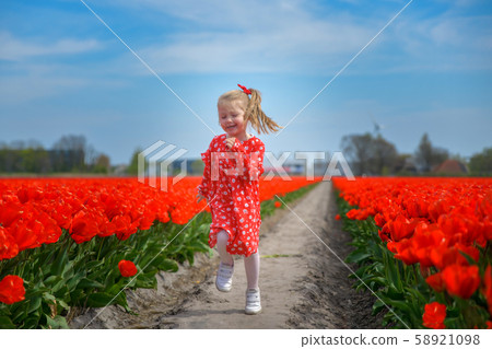 Girl running in a red tulip field 58921098