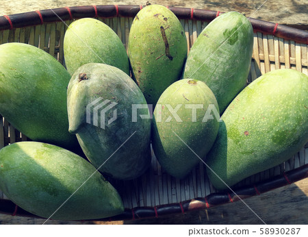 green mango on basket and old wooden desk ,group 58930287