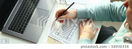 A young designer holds a pen from a tablet in his A young designer holds a pen from a tablet in his 58930356