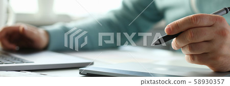 A young designer holds a pen from a tablet in his A young designer holds a pen from a tablet in his 58930357
