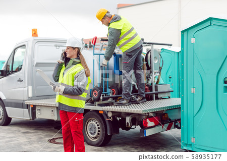 Workers taking care of a delivery of mobile rental toilets 58935177