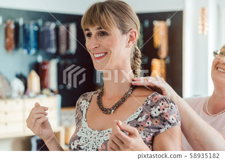 Young woman trying a necklace in the shop 58935182