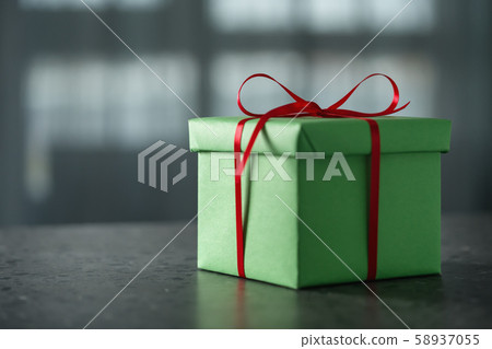 Green gift box with red ribbon against window on terrazo countertop with copy space Green gift box with red ribbon against window on terrazo countertop with copy space 58937055