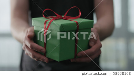 young man show green paper gift box with red ribbon 58938168