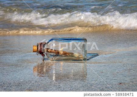 Message in the bottle against the Sun setting down 58938471