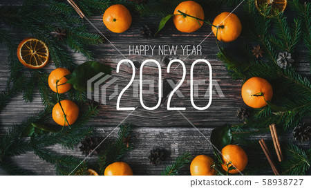 greeting inscription Happy New year 2020 on a wooden background with a frame of tangerines and fir 58938727