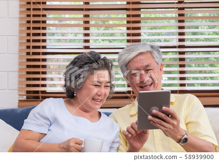 Asian senior couple using table compute and drink coffee sitting at sofa i Asian senior couple using table compute and drink coffee sitting at sofa i 58939900