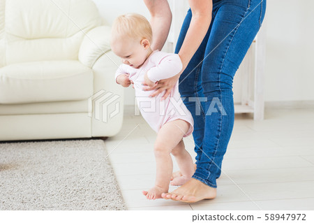 little baby girl first steps with the help of mom little baby girl first steps with the help of mom 58947972