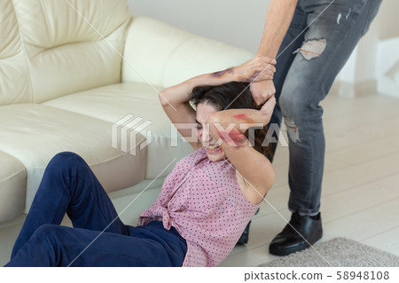 domestic violence, victim and abuse concept - cruel aggressive man grabbing his wife lying on the domestic violence, victim and abuse concept - cruel aggressive man grabbing his wife lying on the 58948108