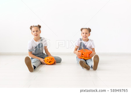 Happy Halloween, holidays and childhood concept - Cute little twins sisters girls with a pumpkins 58949765